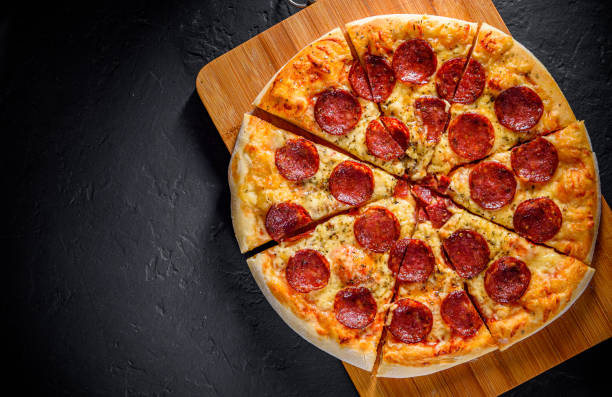pizza pepperoni con mozzarella, salame, salsa di pomodoro, pepe, spezie. pizza italiana su sfondo ardesia nera grigio scuro - salame piccante foto e immagini stock