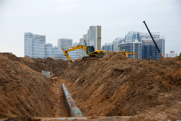Excavator at construction site during laying sewer and main reticulation systems. Civil infrastructure pipe, water lines, sanitary sewers and storm sewers. Underground utilities installation