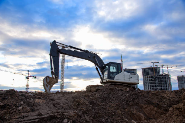 istock Excavator with bucket at large scale construction site on awesome blue sky background 1212517931