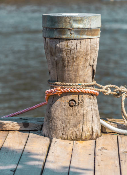 wooden mooring A rope is tied to a wooden mooring bollard with the Yarra River, Melbourne, Australia in the background mooring line stock pictures, royalty-free photos & images