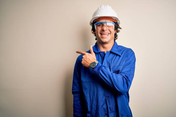 istock Young constructor man wearing uniform and security helmet over isolated white background cheerful with a smile of face pointing with hand and finger up to the side with happy and natural expression on face 1212519945