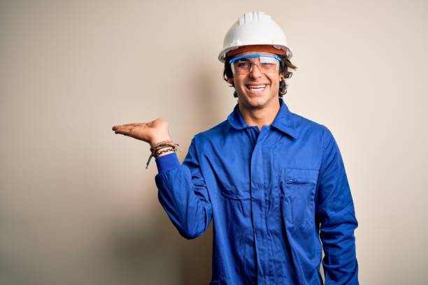 istock Young constructor man wearing uniform and security helmet over isolated white background smiling cheerful presenting and pointing with palm of hand looking at the camera. 1212519948