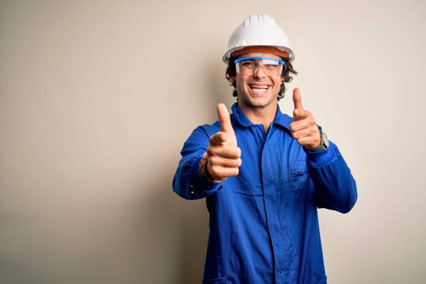 istock Young constructor man wearing uniform and security helmet over isolated white background pointing fingers to camera with happy and funny face. Good energy and vibes. 1212519951