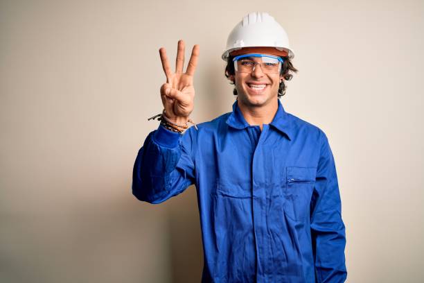 istock Young constructor man wearing uniform and security helmet over isolated white background showing and pointing up with fingers number three while smiling confident and happy. 1212519980