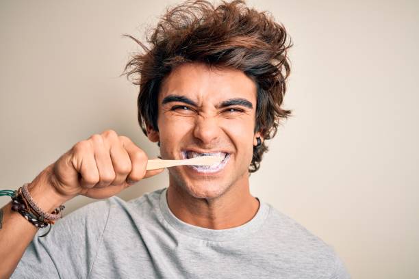 young handsome man smiling happy. standing with smile on face whasing tooth using toothbrush over isolated white background - hairstyle crest imagens e fotografias de stock