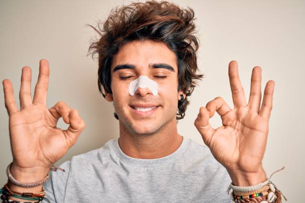 istock Young handsome man using nose strip standing over isolated white background relax and smiling with eyes closed doing meditation gesture with fingers. Yoga concept. 1212520031