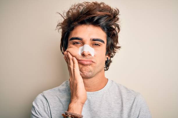 Young handsome man using nose strip standing over isolated white background thinking looking tired and bored with depression problems with crossed arms.