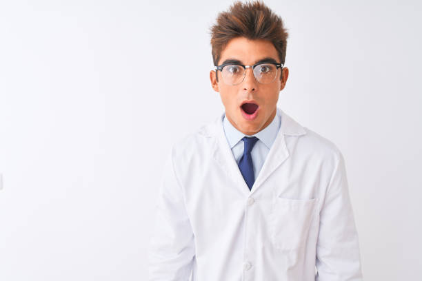 istock Young handsome sciencist man wearing glasses and coat over isolated white background afraid and shocked with surprise and amazed expression, fear and excited face. 1212521119