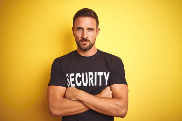 istock Young safeguard man wearing security uniform over yellow isolated background skeptic and nervous, disapproving expression on face with crossed arms. Negative person. 1212524741
