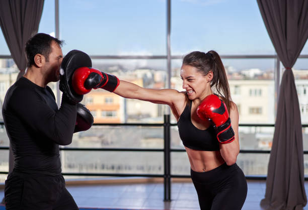 istock Lady boxer hitting the pads with coach 1212526537