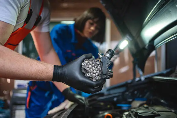 Young female and a male coworkers mechanics working together at a auto repair shop.