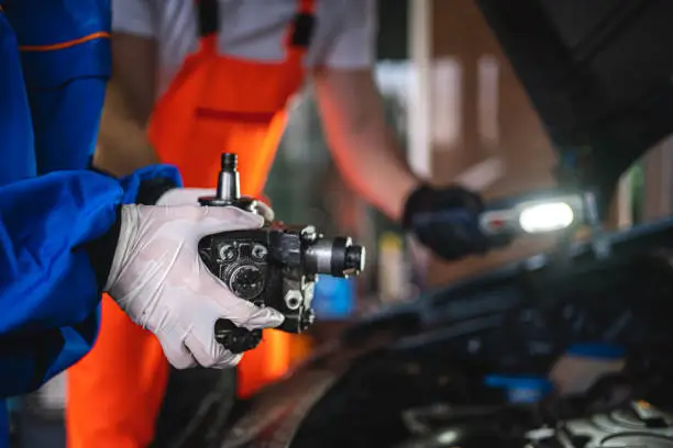 Unrecognizable female and a male coworkers mechanics working together at a auto repair shop.