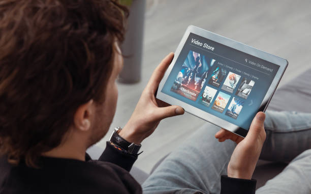 homme utilisant la tablette pour regarder le service de vod - streaming media service photos et images de collection