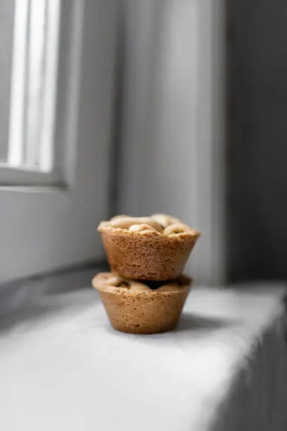 Two pieces of mini homemade applepie in front of a window with soft light