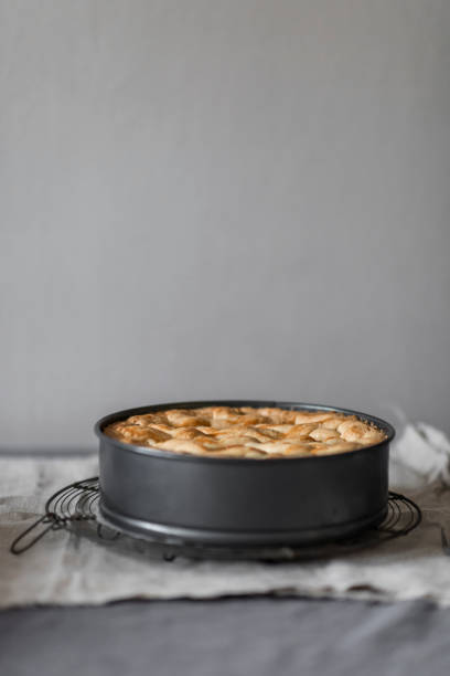 Home made applepie in black baking mold on natural grey linen with two forks