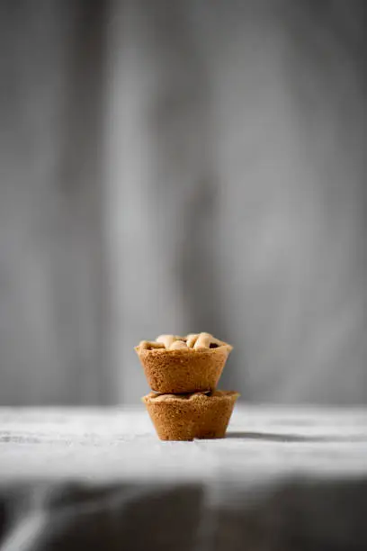 Two pieces of mini homemade applepie on soft grey background