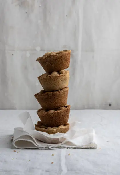 Stack of five mini home made apple cake on white linen and baking paper in front of a light grey painted backdrop