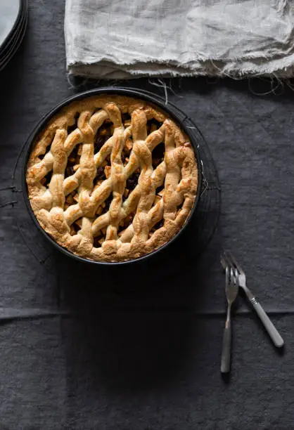 Home made applepie in black baking mold on linen with two forks