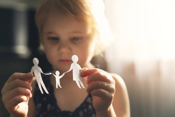 petite fille avec la famille de papier dans des mains. concept de divorce, de garde et de maltraitance d’enfants - divorce photos et images de collection