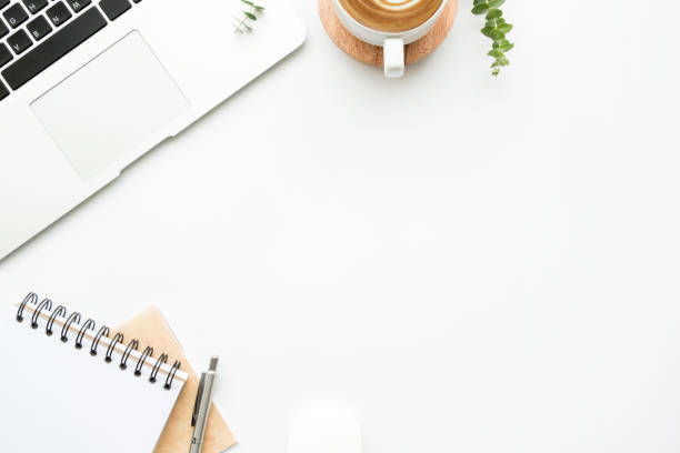 istock White minimalist office desk table with laptop computer, cup of latte coffee, notebooks with pen and supplies. Top view with copy space, flat lay, minimal style. 1212535005
