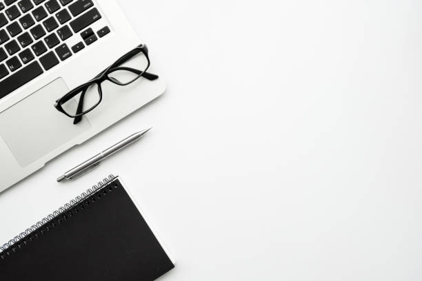 istock White minimalist office desk table with laptop computer, notebook with pen and eye glasses. Top view with copy space, flat lay minimal style. 1212535007