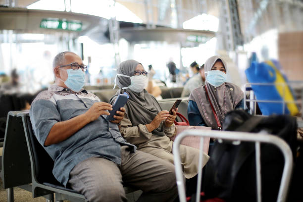 South East Asia: Muslim Family Travel A Muslim senior man and two senior women are  sitting patiently waiting for flight boarding at Malaysia airport. kuala lumpur airport stock pictures, royalty-free photos & images