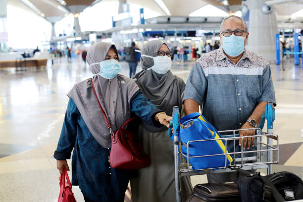 South East Asia: Muslim Family Travel A senior Muslim man and two senior women pushing trolley at Malaysia airport waiting for flight boarding. klia airport stock pictures, royalty-free photos & images