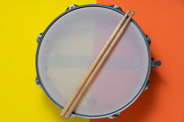 istock Drum stick and drum on yellow and orange table background, top view, music concept 1212536685