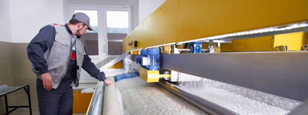 Laundry worker in the process of working on automatic machine for carpet washing in dry cleaning
