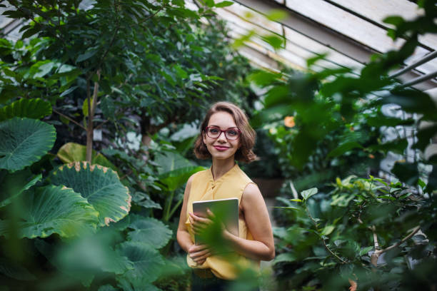 istock Young woman with tablet standing in botanical garden. Copy space. 1212538656