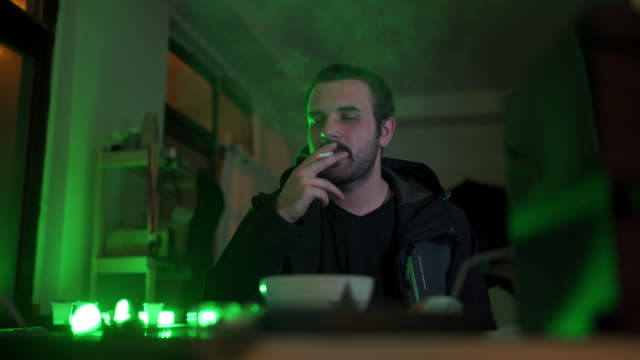 Skilled hacker smoking cigarette while analyzing the back door