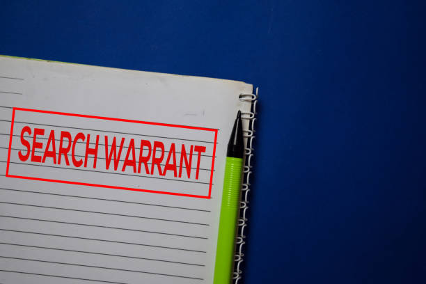 istock Search Warrant write on a book isolated on blue background. 1212539960