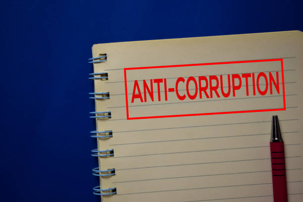 istock Anti-Corruption write on a book isolated on blue background. 1212539973
