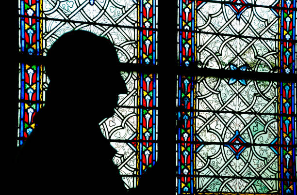 man praying in front of stained glass window in church man praying in front of stained glass window in church priest photos stock pictures, royalty-free photos & images