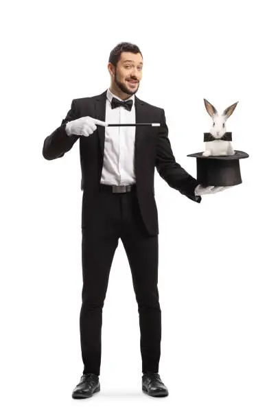 Full length portrait of a magician performing a trick with a hat and a rabbit isolated on white background