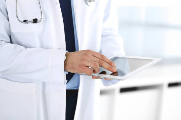 istock Doctor man using tablet computer for network research or virtual disease treatment, hands close-up. Perfect medical service in clinic. Modern medicine, medic data and healthcare concepts. Toned picture 1212543297