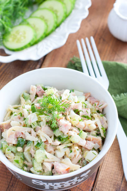 istock Smoked chicken salad with fresh cucumber in a white bowl, selective focus 1212543342