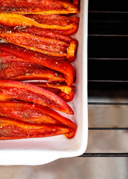 Baked red sweet bell pepper in a white ceramic baking dish. Flat lay. Copy space.