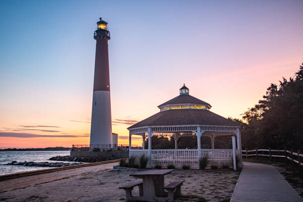 Barnegat Lighthouse stands next to a gazebo at dawn stock photo