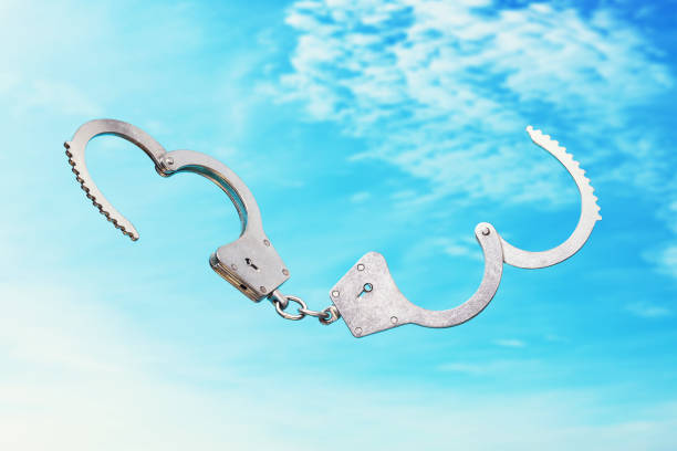 istock Open handcuffs on a sky background as a symbol of freedom 1212550596