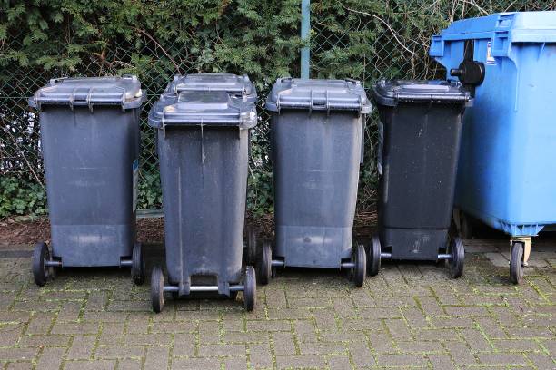 istock dark garbage cans are standing at the fence in a row 1212551419