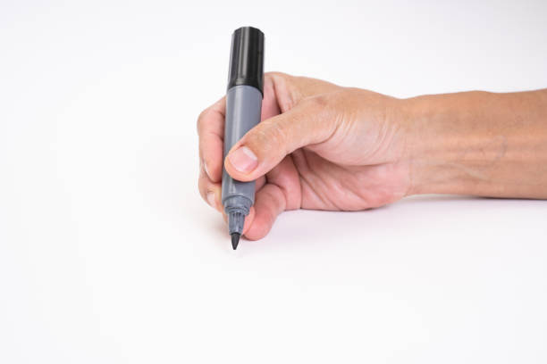 istock Man hand holding black magic marker pen writing on white background 1212552669