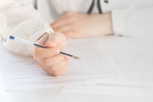 istock Drawing up a tax return. Hands holding a pen for signature 1212552784