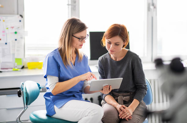 A dentist talking to woman in dentist surgery, a dental check-up. A dentist with tablet talking to woman in dentist surgery, a dental check-up. tablet pc and digital hospital tools stock pictures, royalty-free photos & images