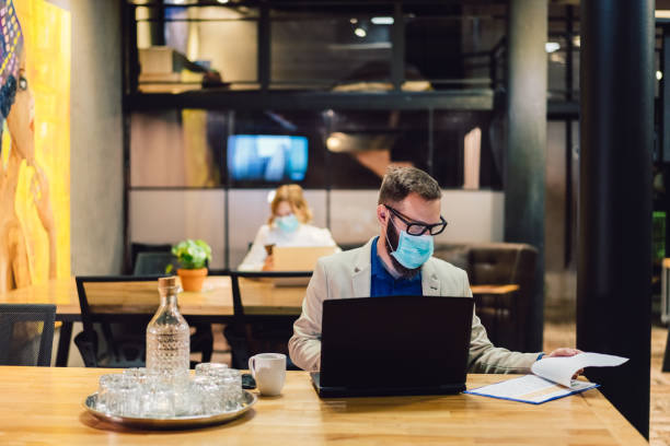 Protection in the office during COVID-19 pandemic Businesspeople wearing masks in the office and working on bigger distance for safety during COVID-19 pandemic avian flu virus photos stock pictures, royalty-free photos & images