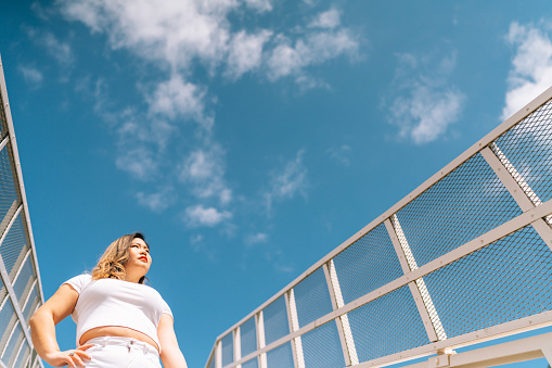 A low angle portrait of young woman while looking away under clear sky.
