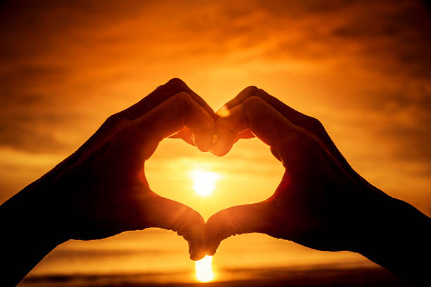 istock Heart formed by a human hand in backlight at sunset 1212557206