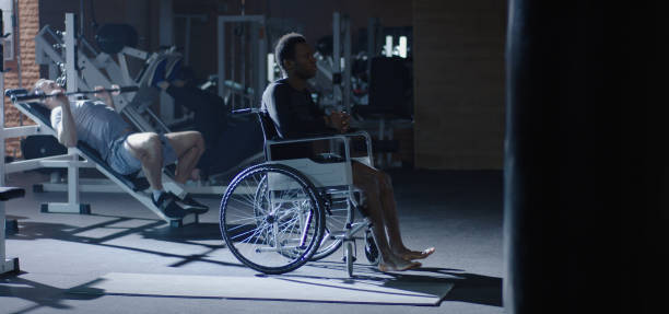 istock Wheelchair man sitting while others working out 1212557581