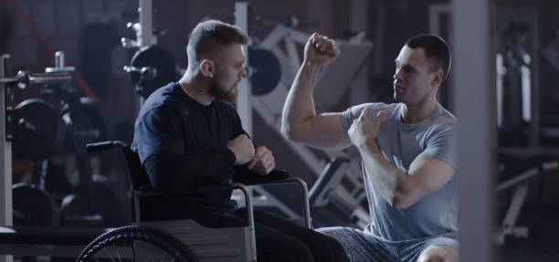 istock Trainer demonstrating exercise for wheelchair man 1212557736