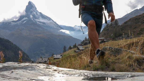 istock Man hikes along through grassy meadow 1212559544